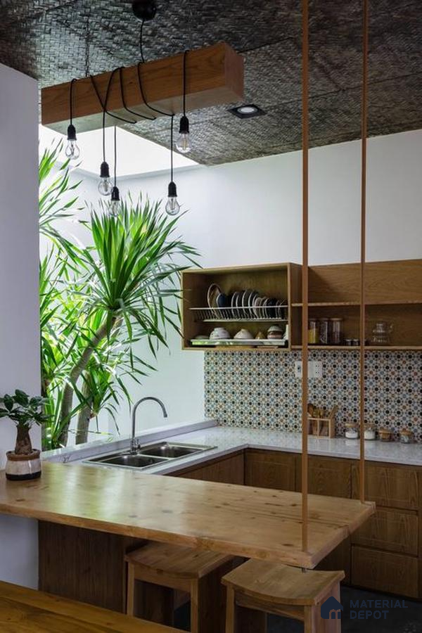 A kitchen with marble counter tops and wooden cabinetry, along with an island in the middle of the middle of the island with stairs leading to shop & more counter top space to an island in the middle of